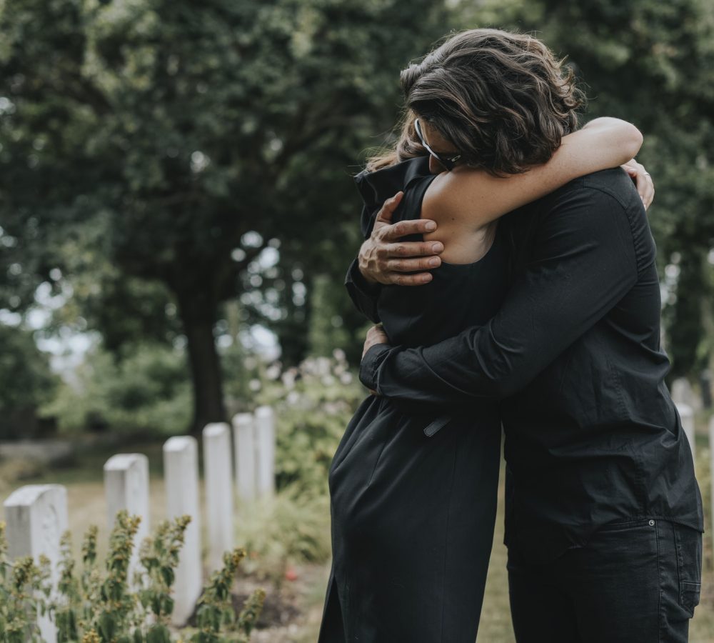 husband-trying-to-comfort-his-wife-at-a-graveyard.jpg
